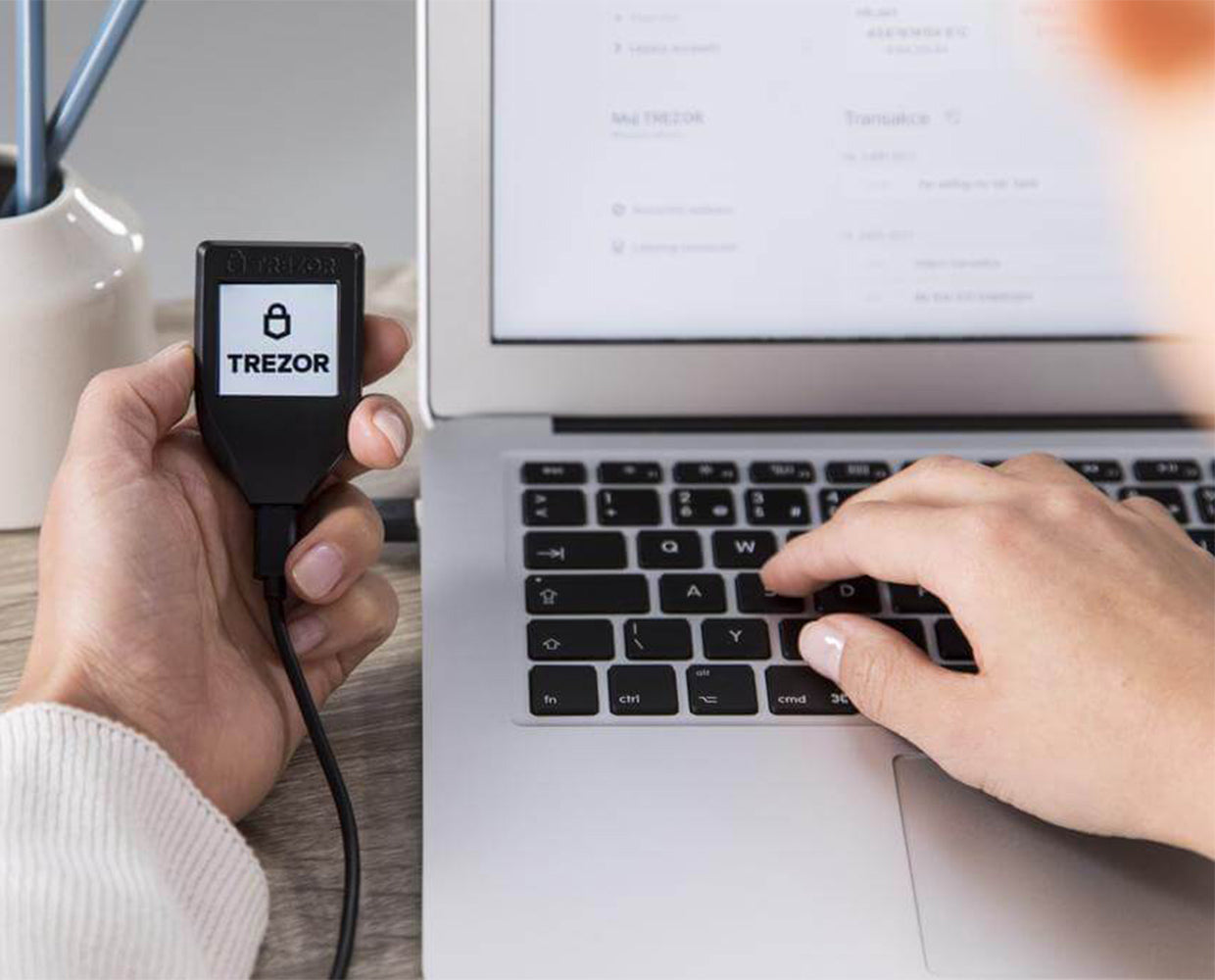 Trezor Model T hardware wallet held beside a laptop